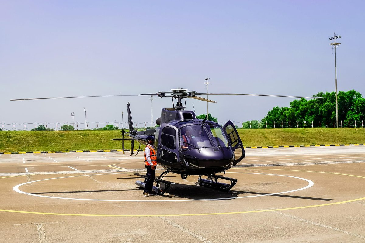 A helicopter on its landing pad with a ground crew member beside it