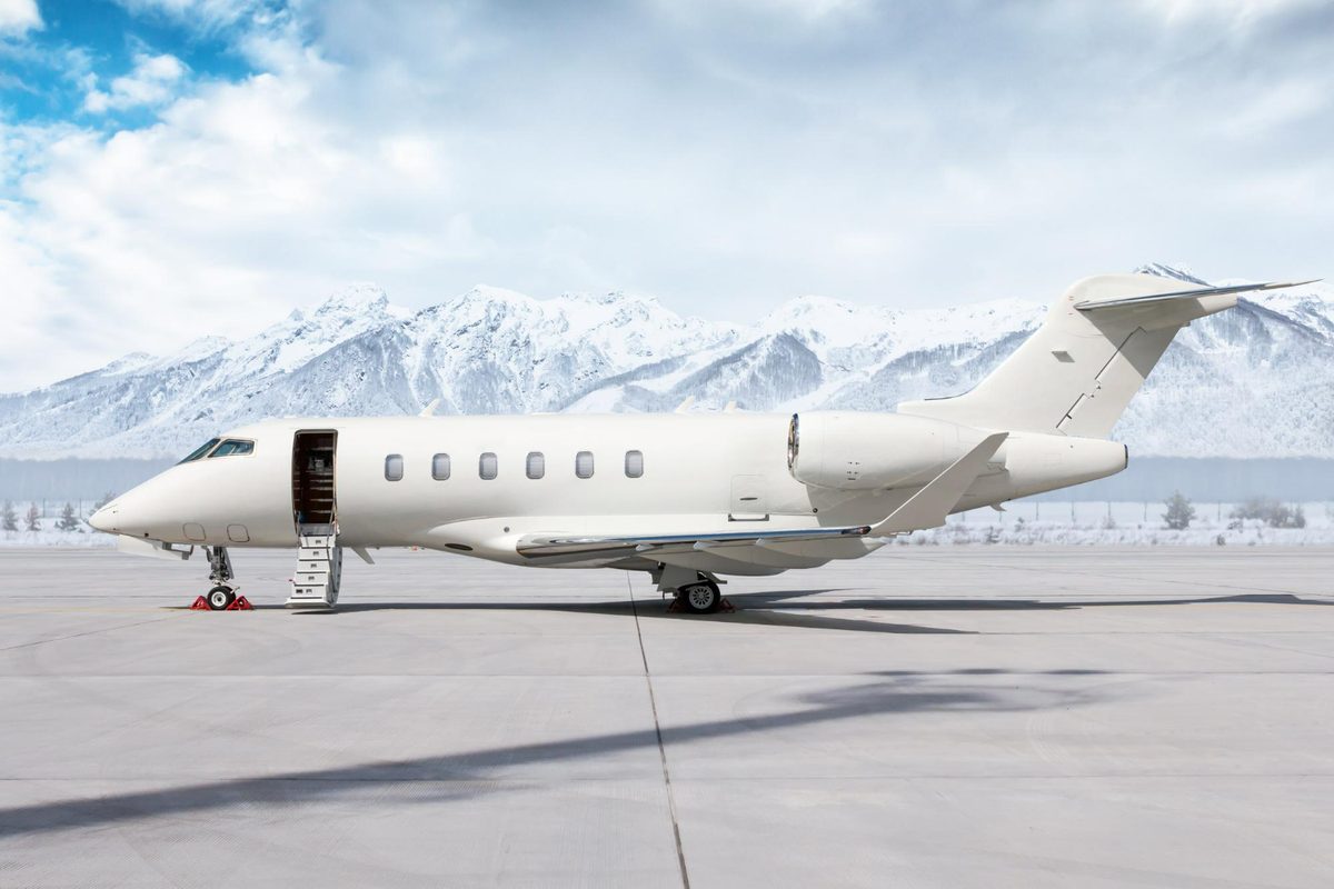 A business jet on the apron with its door open and snow-capped mountains behind