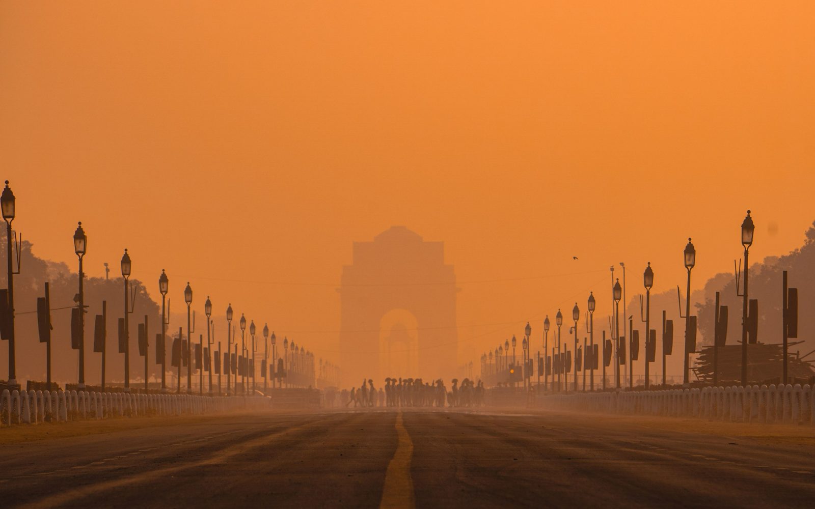 India Gate at the end of a wide avenue in the dawn haze