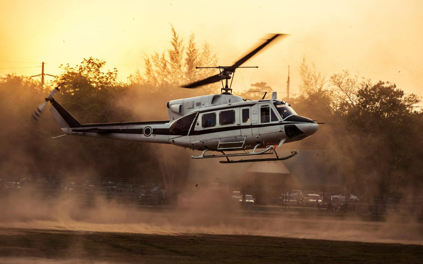 A helicopter lifting off in a cloud of dust at sunset